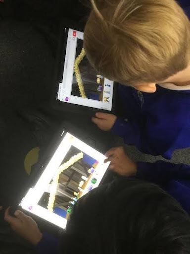 Two young boys from Nursery are seen sitting on the floor, reading picture books about the Nativity story.