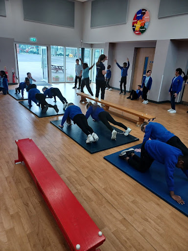 Students at DPA are pictured participating in a Gymnastics exercise, under the supervision of a professional athlete visiting the academy for Sports for Champions Day.