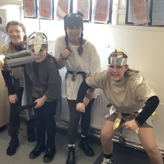 A group of four female pupils are seen posing for the camera, whilst dressed in fancy dress for Year 5 Viking Day.