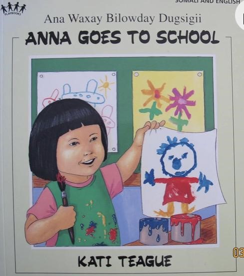 This is a book cover titled "Anna Goes to School" (also in Somali and English) by Kati Teague, showing a child holding up a drawing.