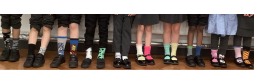 An image of the legs and feet of students, stood in a row, showing their odd socks