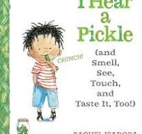 This is a partial cover of the book "I Hear a Pickle (and Smell, See, Touch, and Taste It, Too!)" by Rachel Isadora. The title explicitly mentions the five senses, indicating the children are using this book as a central theme or inspiration for sensory exploration activities.