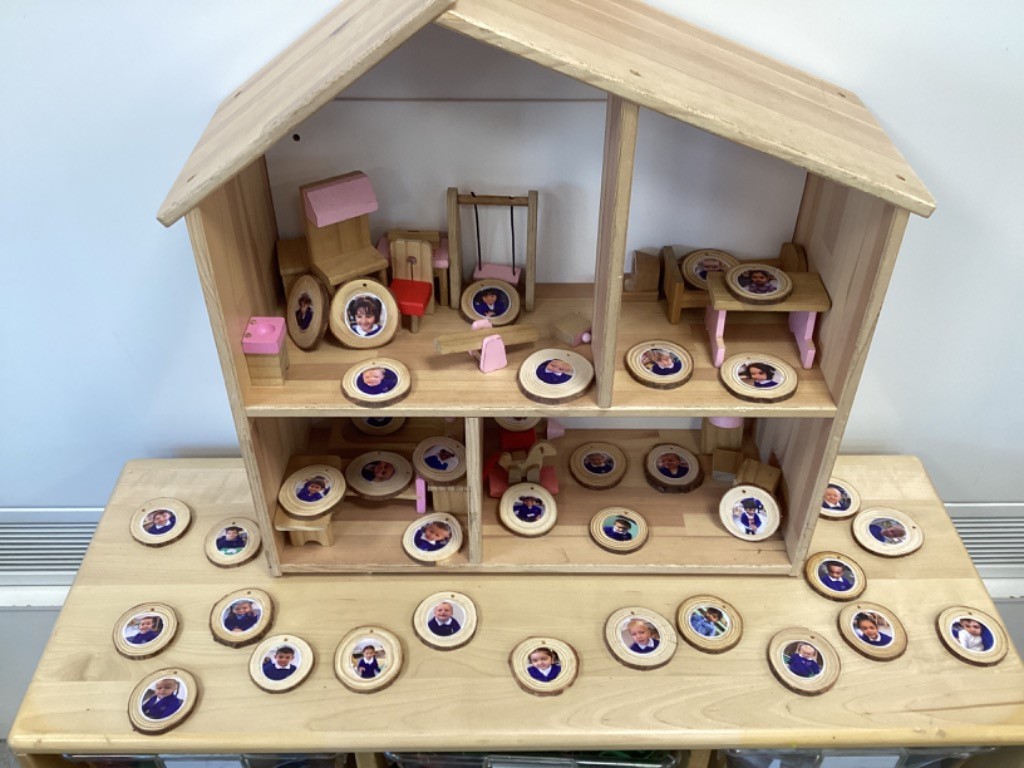 provides a closer look at the dollhouse and the tokens, showing how they are arranged inside and around the house.