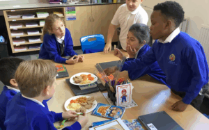 a group of students are having a discussion while sharing a meal or snack at a table.