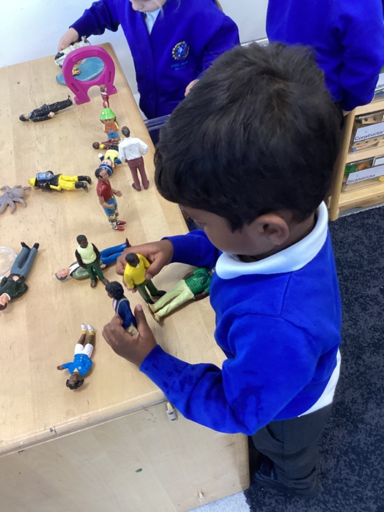 a child is playing with a collection of small toy figures on a table.