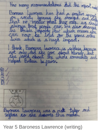 This is a photo of a handwritten passage by a Year 5 (age 9-10) student about Baroness Lawrence. The writing discusses her positive impact on society, including her efforts to change the Double Jeopardy law, and praises her as "selfless." A small drawing of a medal is also included, suggesting she "deserves this medal."