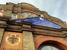 The exterior of a brick building featuring a blue sign that reads "CHÙA DƯỢC SƯ Medicine Buddha Foundation Vietnamese Buddhist Meditation Centre." A smaller wooden sign below indicates "Shaolin Temple."
