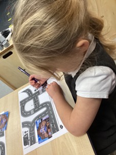 A young child in a uniform working on a paper with a road map design