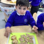 Young boy in blue school jumper holding a tray of bread