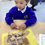Young girl in blue school jumper holding a tray of bread