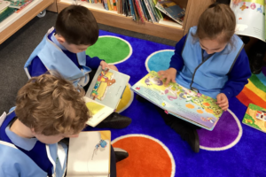 three children reading books in a library setting