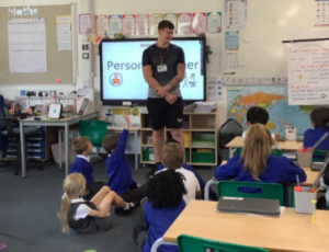 Children in a classroom with an adult personal trainer talking to them