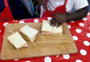 A Child cuts a sandwich into two triangles on a chopping board